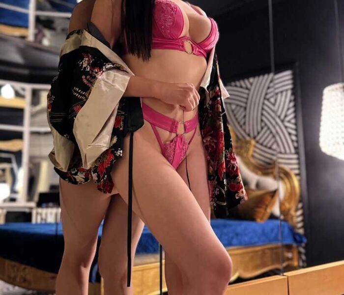 Die Hure Mina aus dem Bordell Herrenhaus Berlin steht in rotem Bikini an einem Spiegel