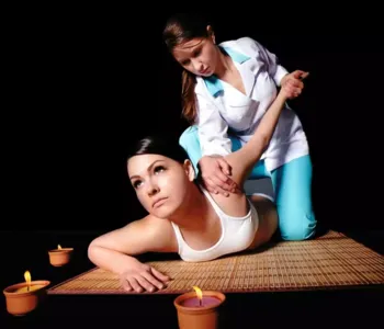 Eine Thai-Masseurin therapiert eine Patientin auf einer Reismatte
