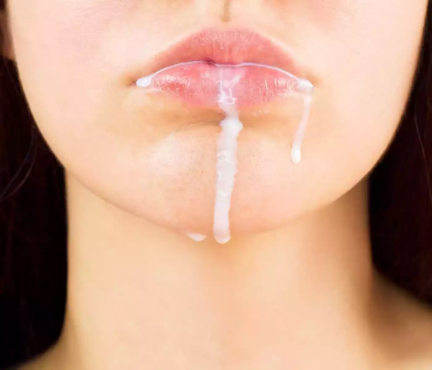Großaufnahme vom Gesicht einer Frau der Sperma aus dem Mund fließt